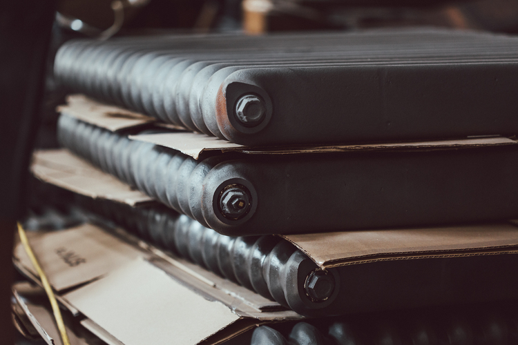 Black reclaimed column cast iron radiators stacked upon one another with sheets of cardboard between.